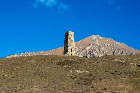 Ancient stone tower on the background of blue mountains Stock Photos
