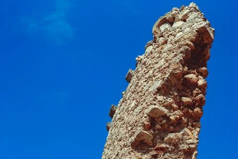 An ancient stone tower on a blue sky background Photos