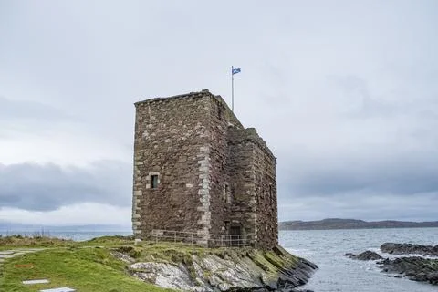 Ancient stone tower stands alone on rocky outcrop Foto stock