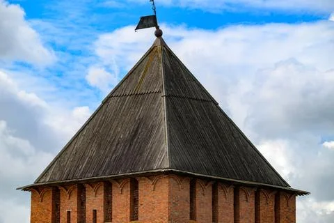 Ancient stone tower with steep thatched roof. Weathered wood shingles show ag Stock Photos