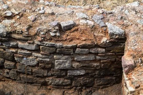 Ancient stone wall built with irregularly shaped rocks. Earthly surface shows Stock Photos