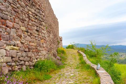 Ancient Stone Wall, Cobblestone Path, and Scenic View in Molyvos, Greece 库存照片
