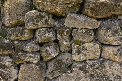 Ancient stone wall covered with moss. A natural stone. Vintage creative backg Stock Photos