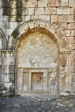 Ancient stone wall featuring an arched niche with a wooden door, showcasing.. Stock Photos