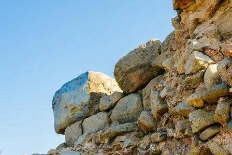 Ancient stone wall ruins with large rocks under clear blue sky Stock Photos