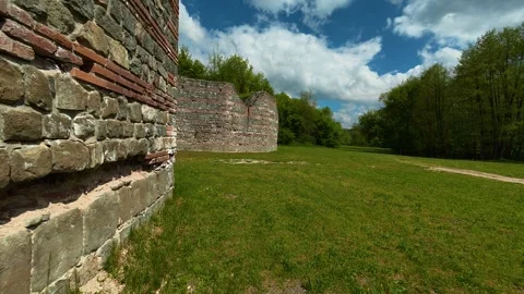 Ancient stone wall stands tall beside a green field. Felix Romuliana, Gamzigrad. Stock Footage 335298349