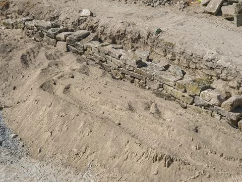 Ancient stone wall under reconstruction with rocks methodically stacked Stock Photos