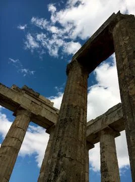 Ancient temple column ruins under blue cloudy sky in Greece Stock Photos