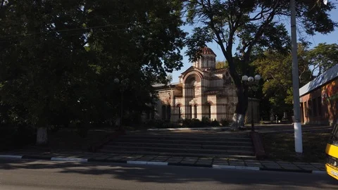 An ancient temple stands in the thick of trees. Cars passing by. Vídeos de archivo 115788780