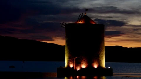 An ancient windmill with romantic lights on the sea bay at sunset Stock Footage 104516992