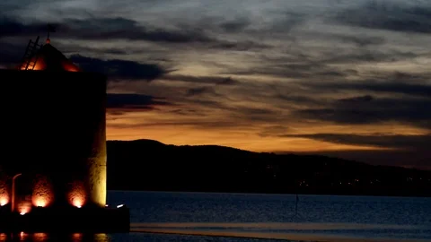 An ancient windmill with romantic lights on the sea bay at sunset Stock Footage 104517002