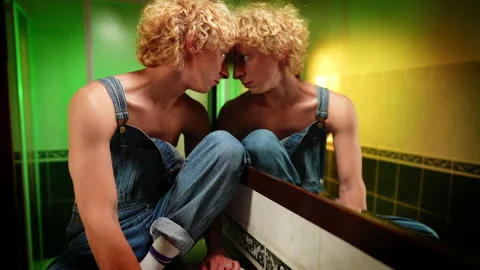 Androgynous Caucasian queer man putting face to mirror looking at reflection Stock Footage 160583079