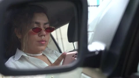 Androgynous young looking your mobile at car in the rear view mirror Stock Footage 194863620