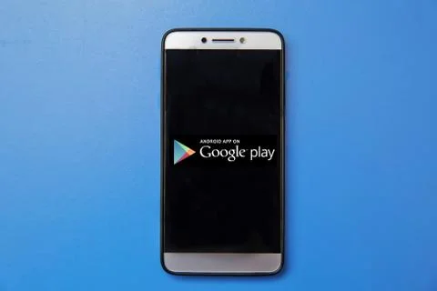 Android Google Play store logo on smartphone screen on blue background. Man Stock Photos