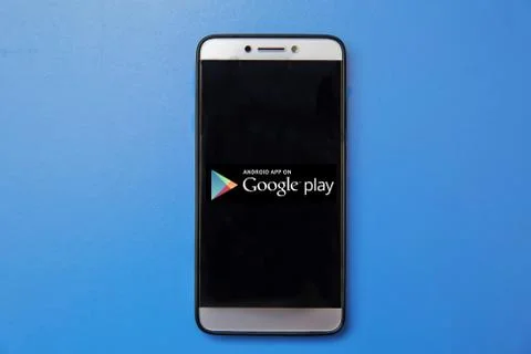 Android Google Play store logo on smartphone screen on blue background. Man h Stock Photos