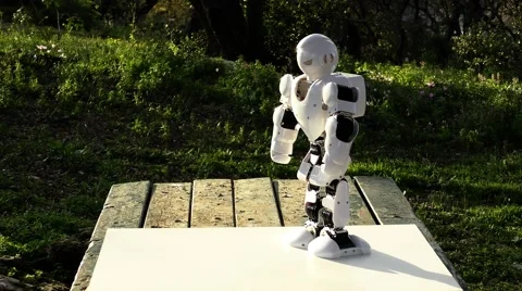 An android humanoid robot practices push ups upside down in the park, falls Stock Footage 60574814