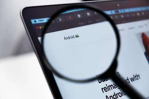 Android logo enlarged through a magnifying glass on a laptop screen Stock Photos