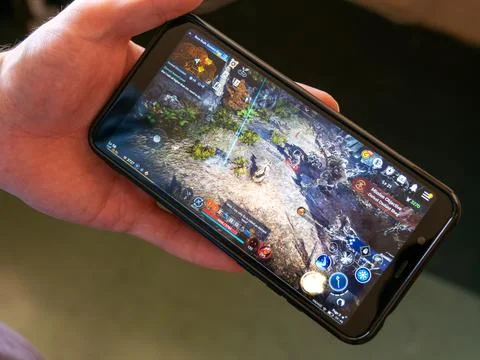 A android smartphone in the hands of a white man. Playing mobile MMORPG Stock Photos