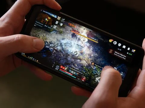 A android smartphone in the hands of a white man. Playing mobile MMORPG Stock Photos