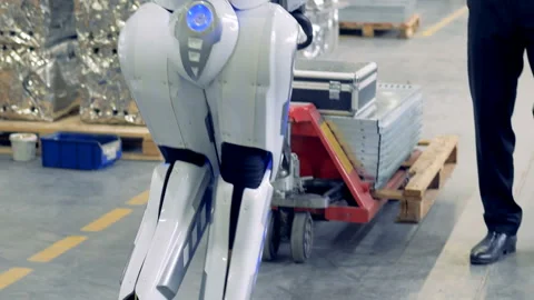 Android is walking backwards and pulling a transporter under control of a male Stock Footage 90900135