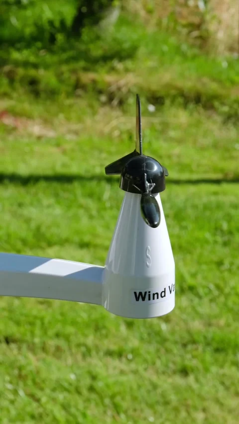 Anemometer measuring wind direction outdoors on a green grass background Stock Footage 346548041