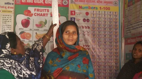 Anganwadi worker measures height of young pregnant woman to predict healthy Stock Footage 315862206