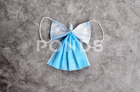 Angel from blue face protection mask on a gray concrete background.COVID-19. Stock Photos