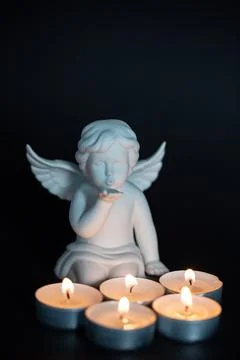 Angel with candles in front of it, black background, mourning card, card, pos Stock Photos