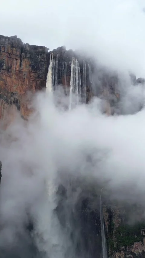 Angel Falls waterfall through the clouds. A huge flow of water falls from the Stock Footage 303739553