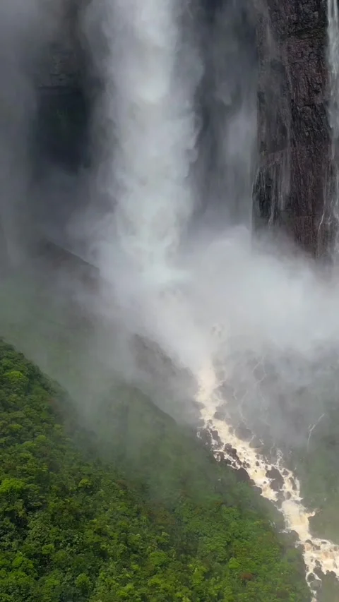 Angel Falls waterfall through the clouds. A huge flow of water falls from the Stock Footage 303739706