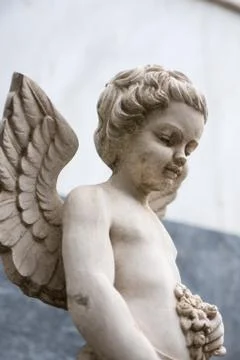 An Angel looking down, with one hand holding a bunch of leaves or flowers Stock Photos