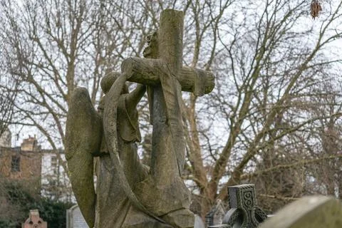Angel statue embracing a cross Stock Photos