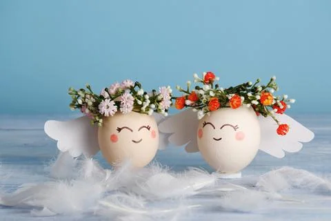 Angels easter egg with flower wreath on pastel blue background. Stock Photos