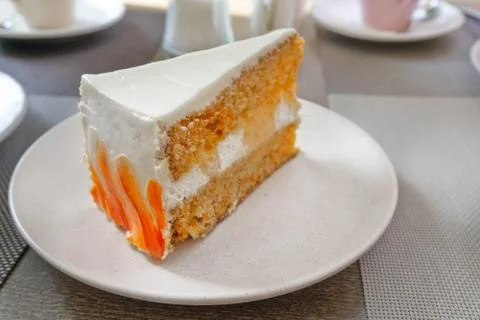 Angle closeup view of big slice of carrot cake on a white plate in a cafe Stockfoto's