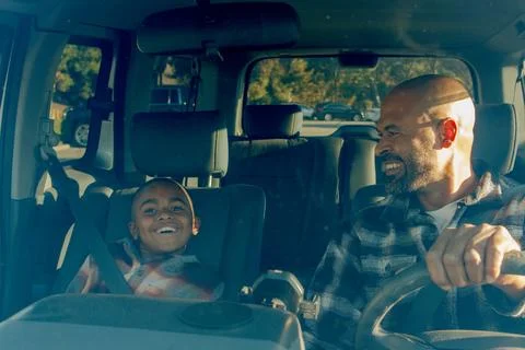 Angle from front window of car of father driving with son happily on a roadtrip Stock Photos
