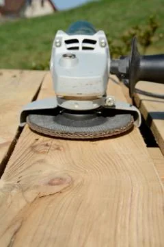 Angle grinder with abrasive disc on plank after work. Blurred background. Foc Stock Photos