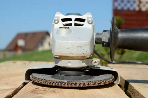 Angle grinder with abrasive disc on planks after work closeup. Stock Photos