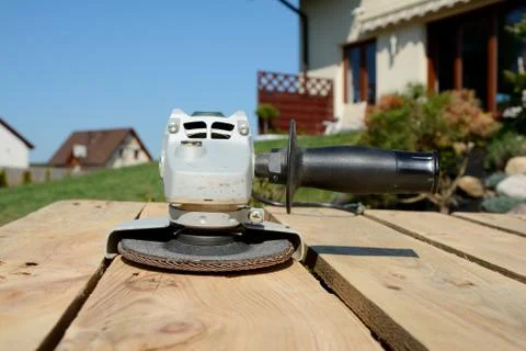 Angle grinder with abrasive disc on planks after work. Stock Photos