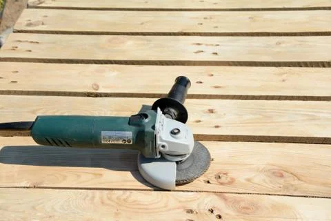 Angle grinder with abrasive disc on planks after work. Stock Photos