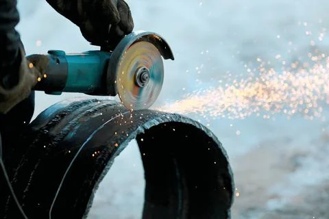 The angle grinder cuts a large-diameter metal pipe and sparks fly. Close-up o Stock-Fotos