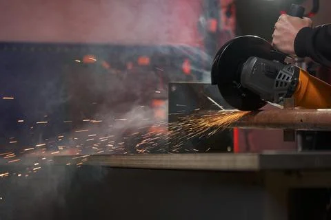An angle grinder with a cutting disc saws a metal pipe detail on a carpentry Stock Photos