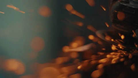 Angle grinder cutting metal and throwing sparks inside dark workshop Stock Footage 331754641