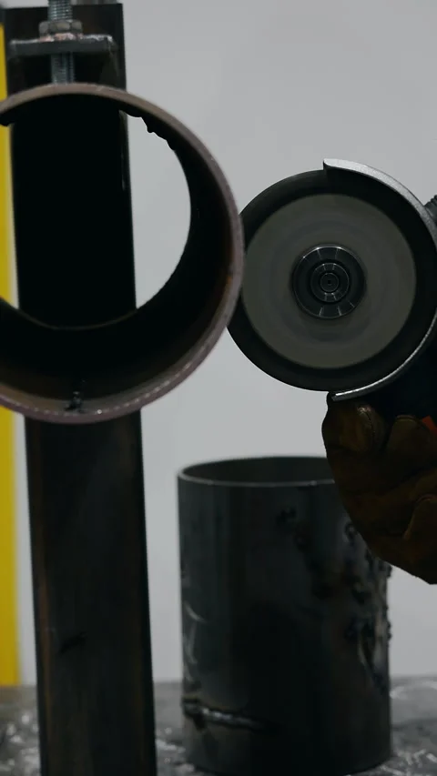 Angle grinder cutting metal pipe with sparks in workshop. Stockbeeldmateriaal 347788856