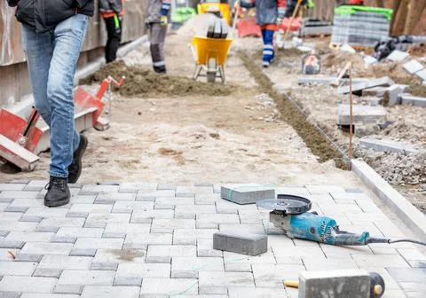 An angle grinder with a diamond cutting disc and paving slabs lies on the sid Foto stock