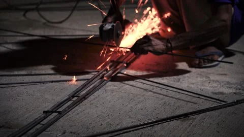 Angle Grinder Grinding Metal Rods With Sparks on Concrete Floor Stock Footage 336949994