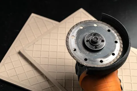 Angle grinder machine and ceramic tile on black work table Photos