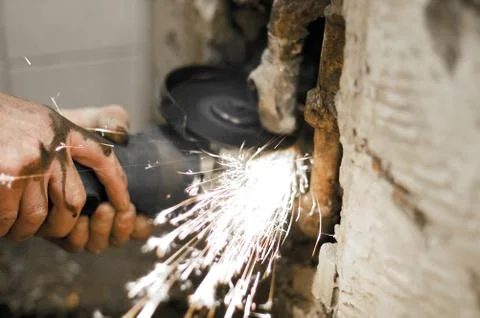 Angle grinder in use, cutting pipes for waterwork. Stock Photos