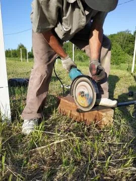An angle grinder worker cuts a metal profile on the outside. 스톡 사진