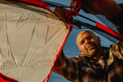 Angle from inside tent of dad helping to put together camping tent Stock Photos