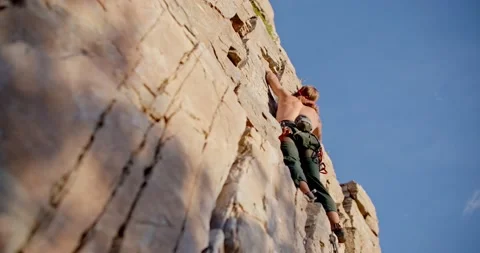 Up angle of rock climber standing on rock wall 库存影片 209338341